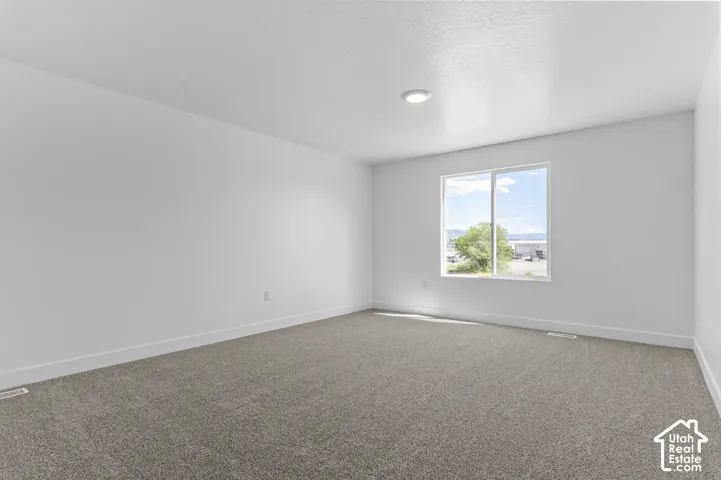 Recessed ceiling lighting, white painted walls, large window with white frame, gray carpeting, and white trim