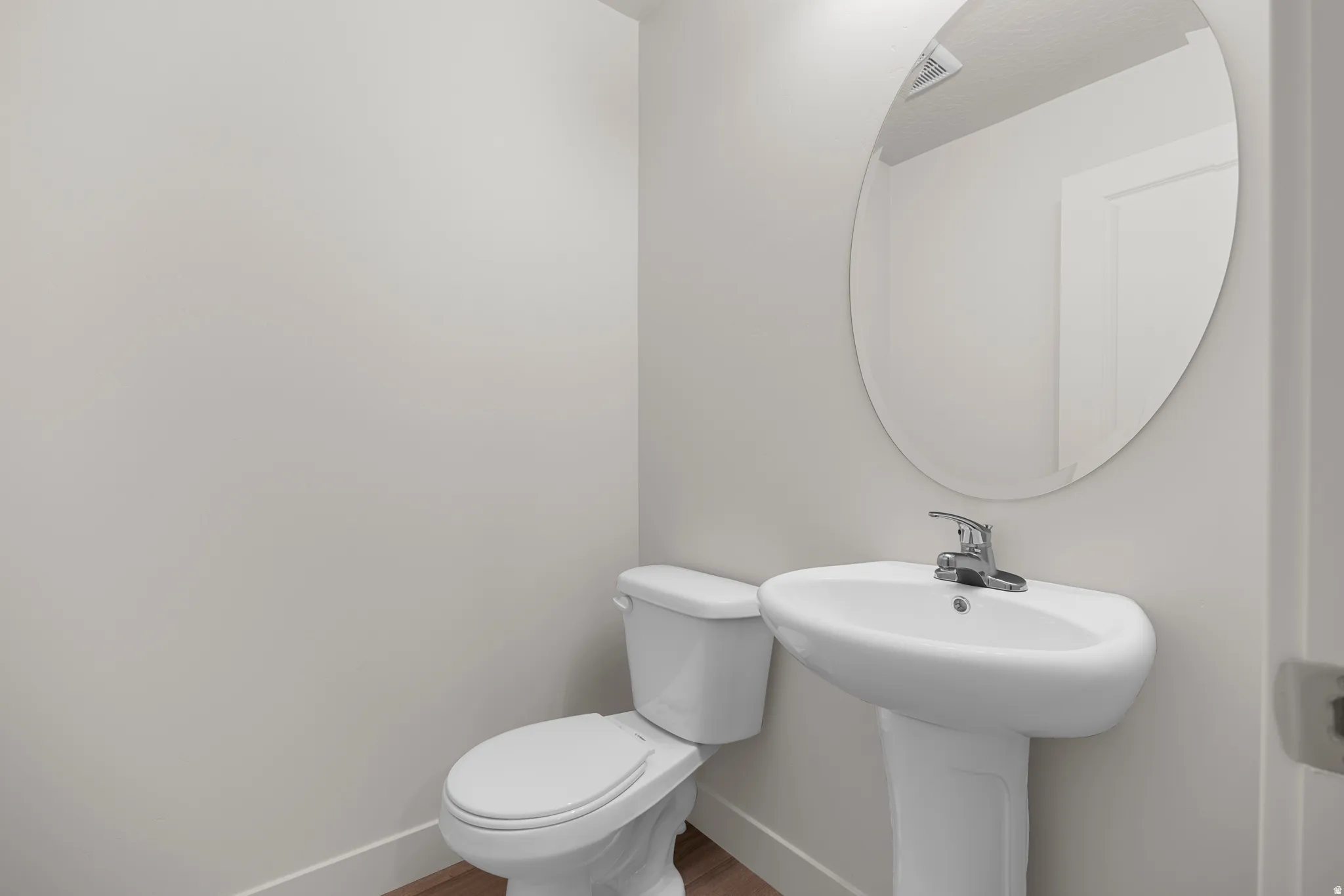 Half bath featuring baseboards and wood finished floors