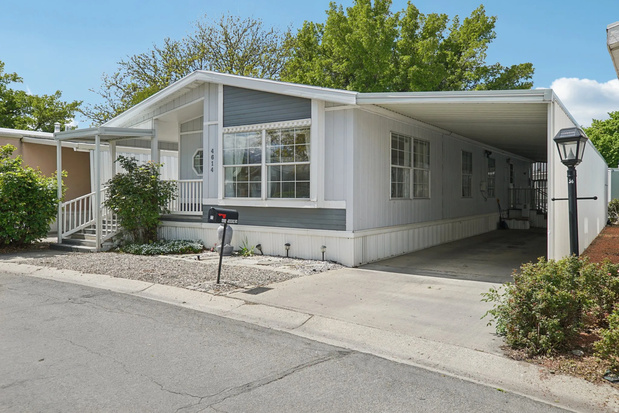 Manufactured / mobile home with a carport, driveway, and covered porch