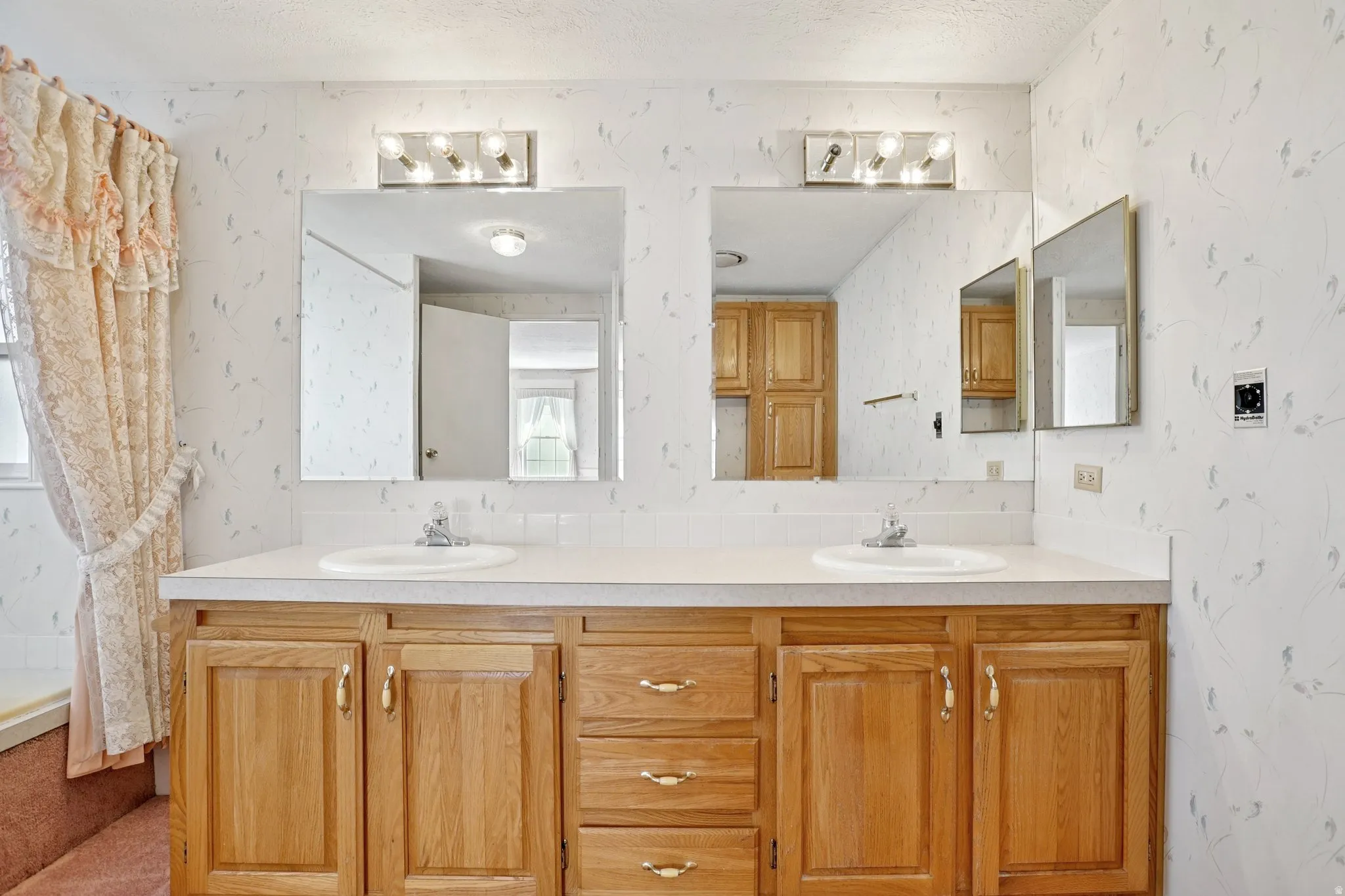 Bathroom with double vanity, wallpapered walls, and a shower with curtain