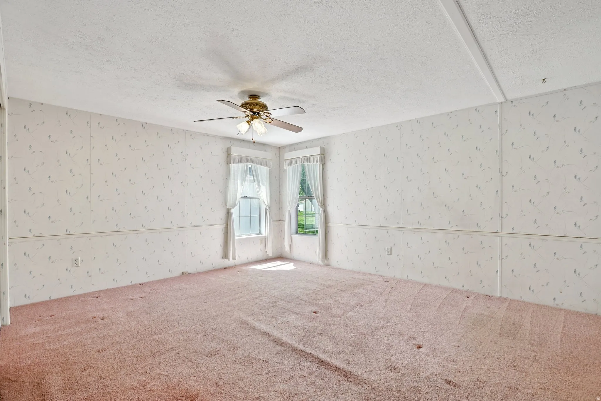 Carpeted spare room with a textured ceiling, wallpapered walls, and ceiling fan