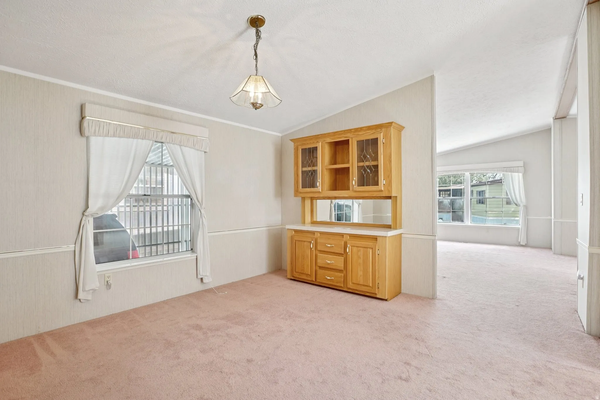 Dining room featuring light colored carpet and lofted ceiling
