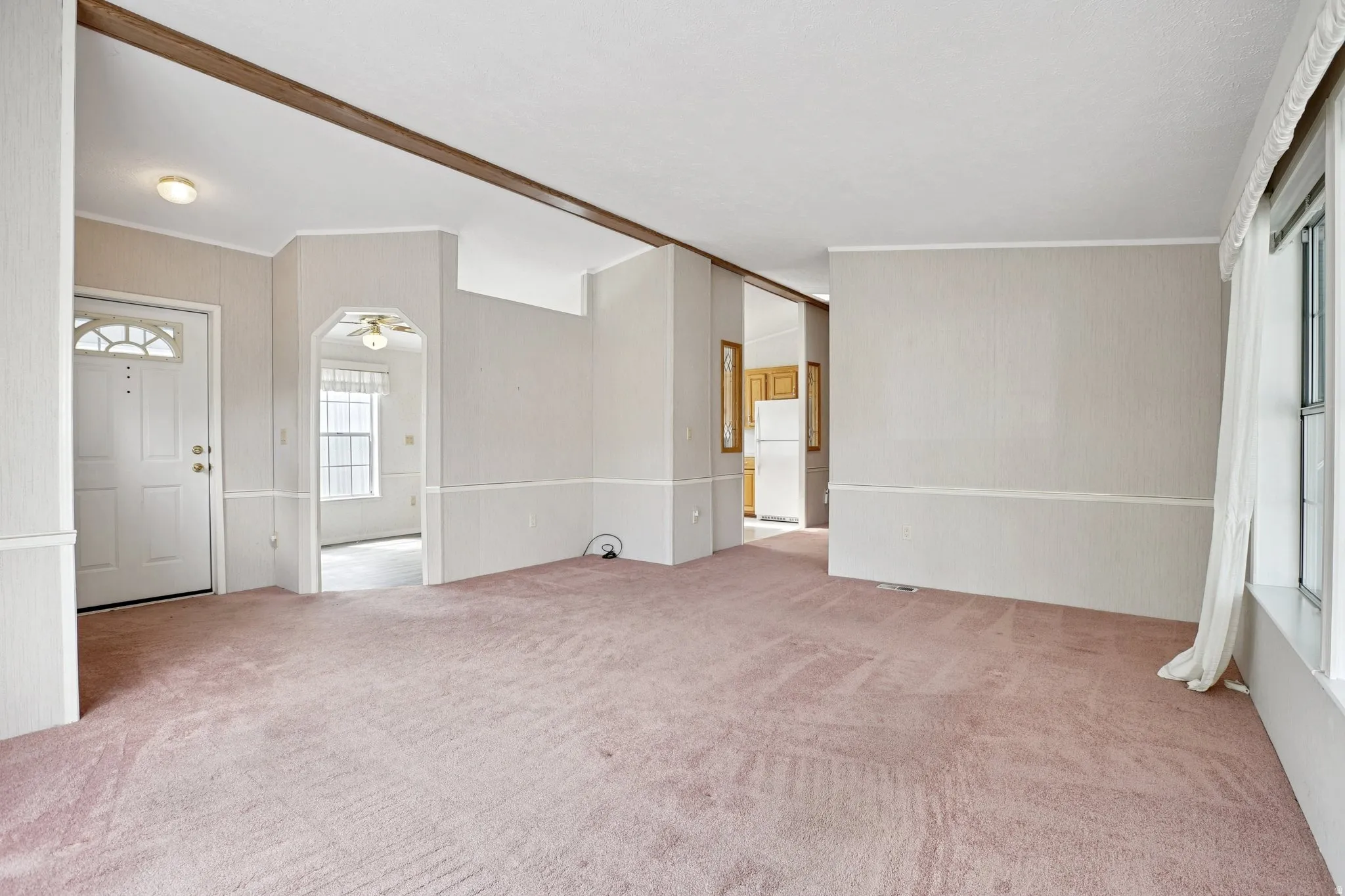 Foyer entrance featuring light carpet, arched walkways, ornamental molding, and a ceiling fan