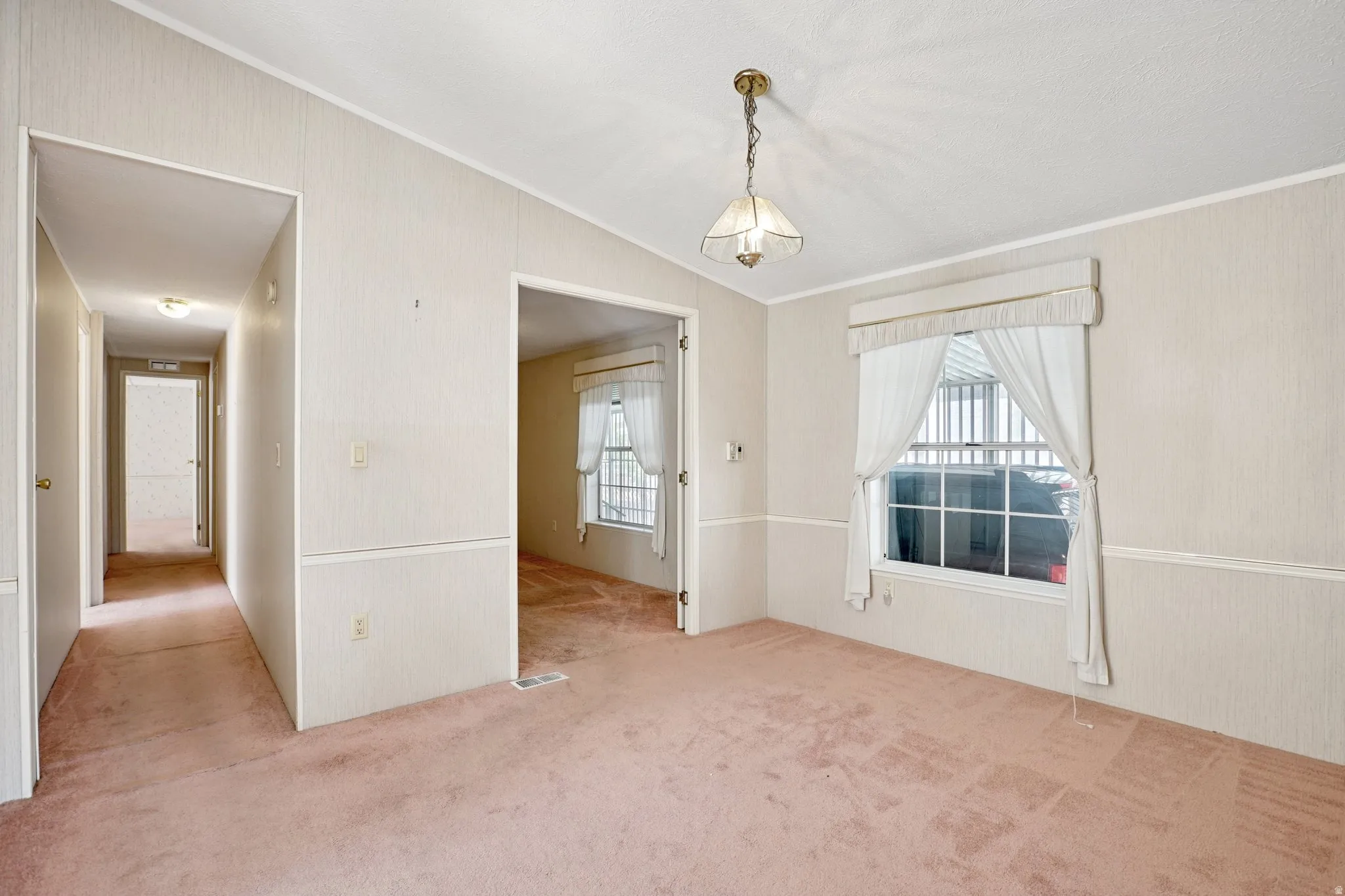 Unfurnished dining area featuring light colored carpet, vaulted ceiling, ornamental molding, and wood walls