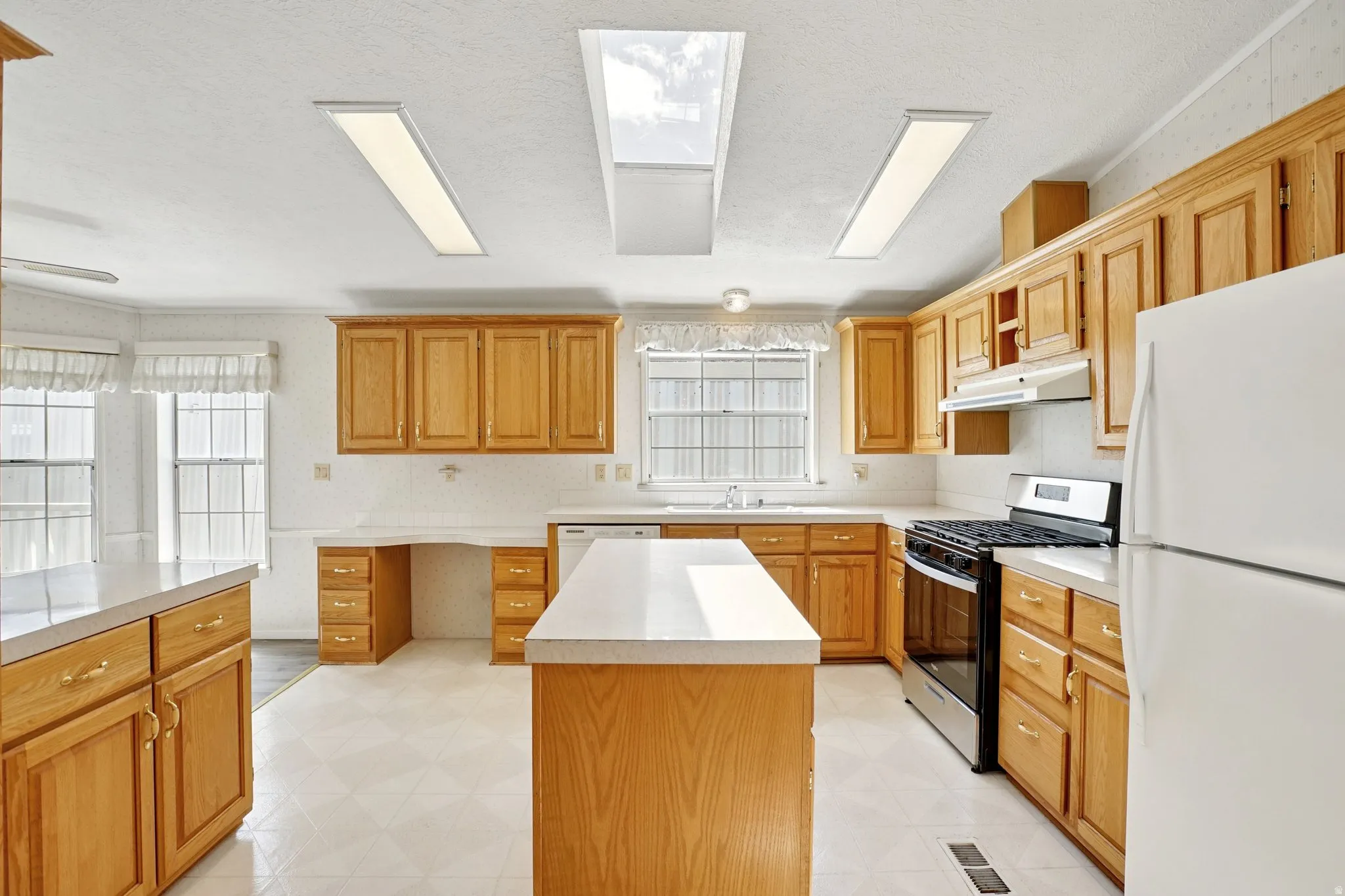 Kitchen with white appliances, light flooring, light countertops, and a center island