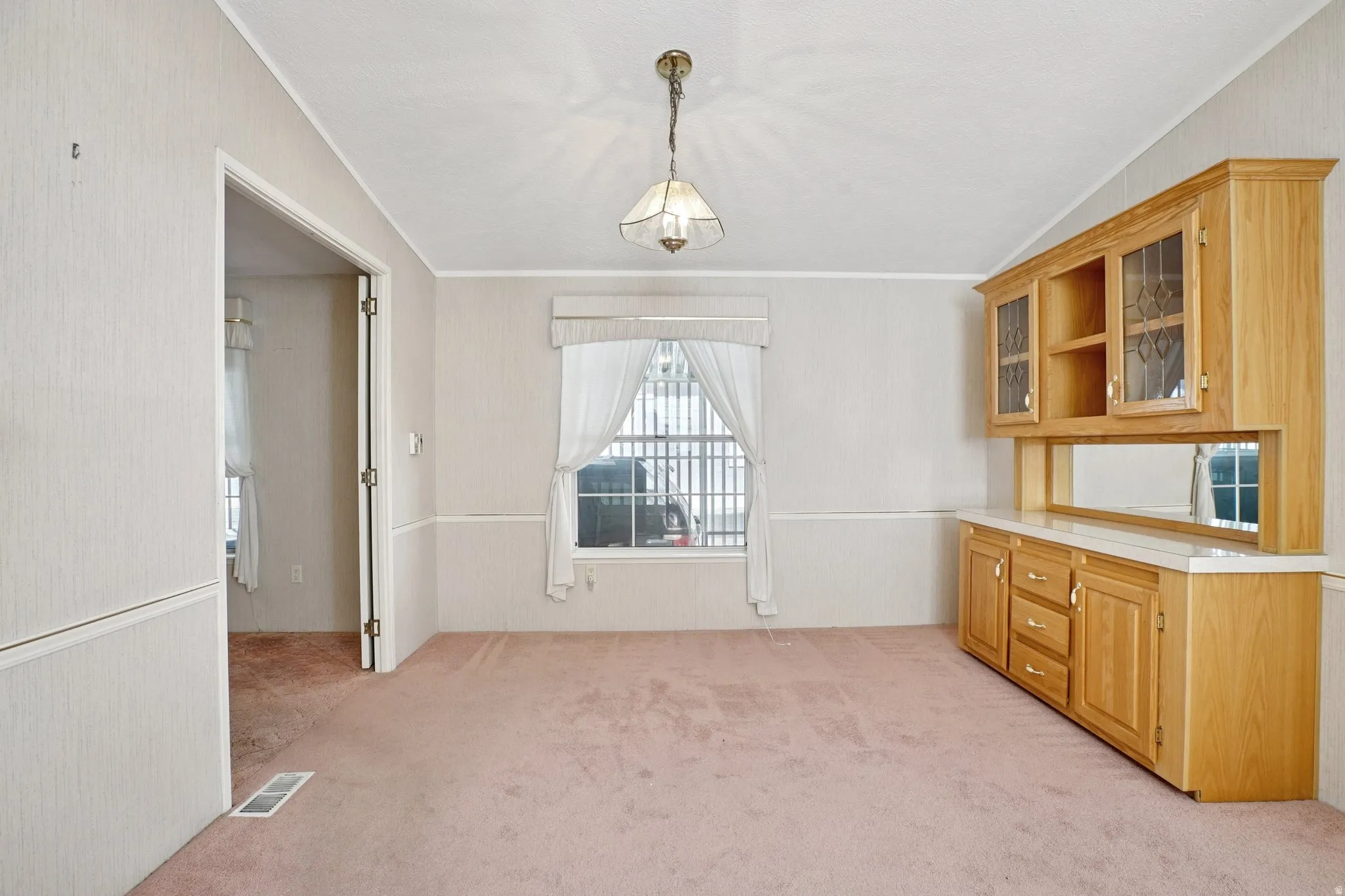 Unfurnished dining area with light colored carpet and crown molding