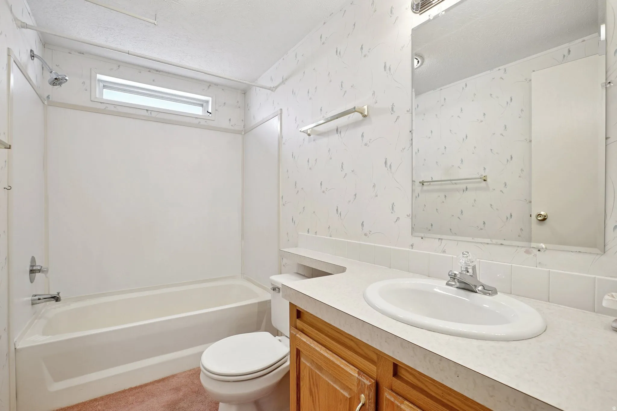 Bathroom featuring wallpapered walls, vanity, bathing tub / shower combination, and a textured ceiling