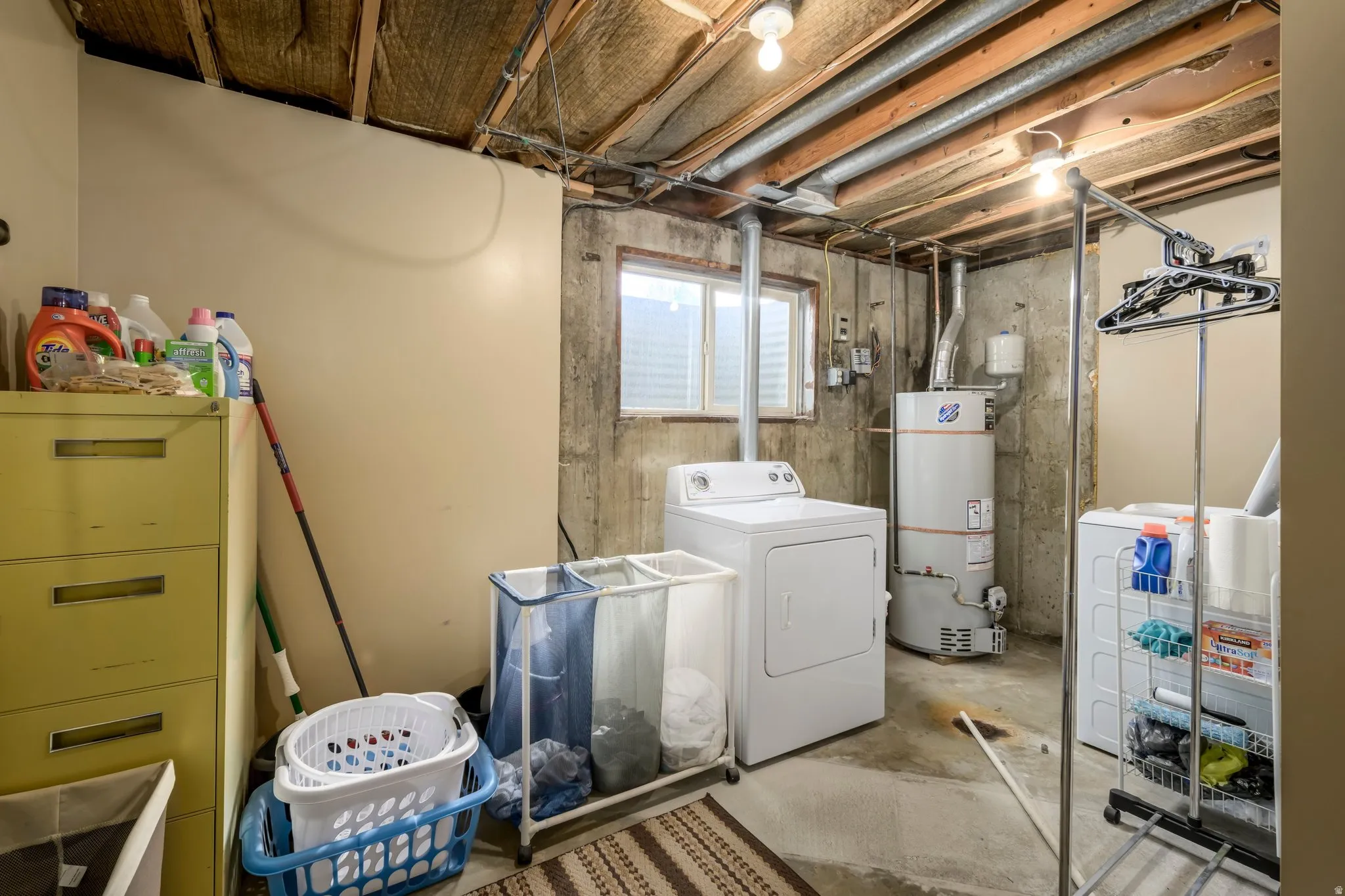 Laundry area featuring washer / clothes dryer, concrete floors, and gas water heater