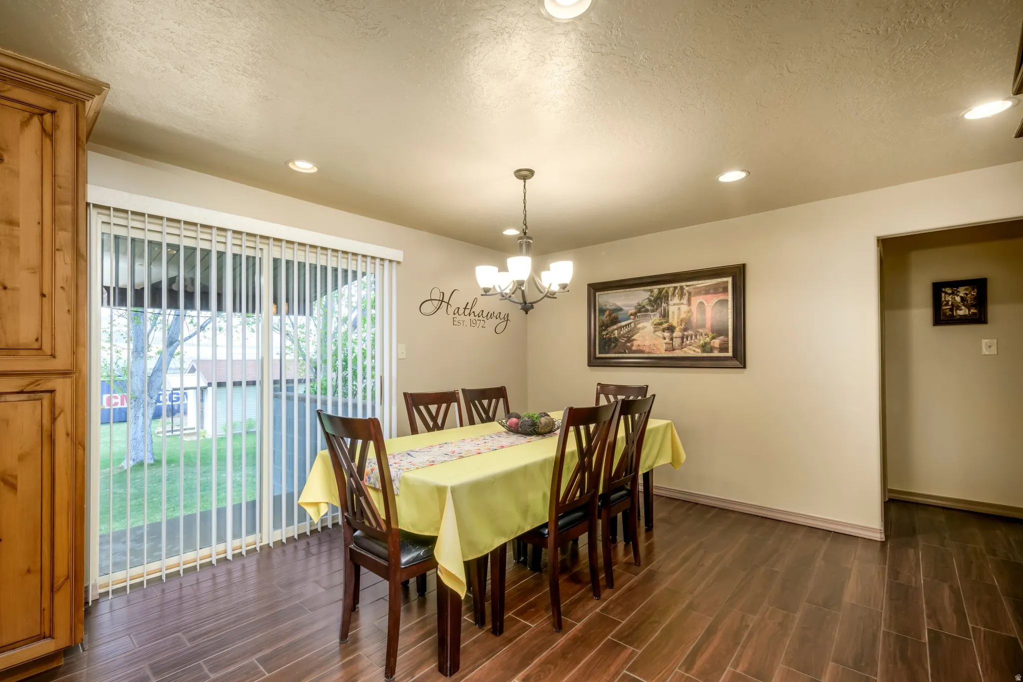 Dining space with a textured ceiling, wood tiled floors, and hanging lights