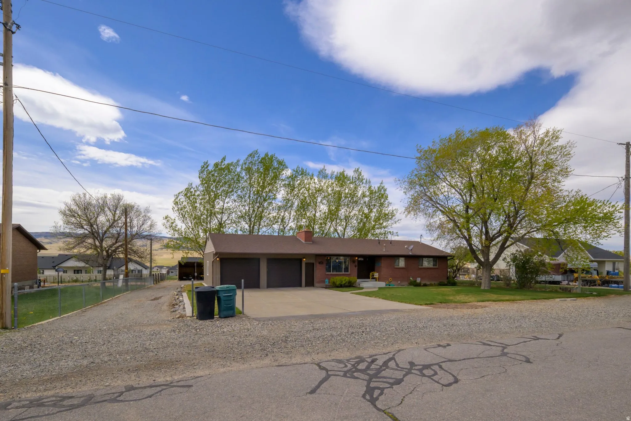 Ranch-style home with concrete driveway, a garage, a residential view, a chimney, and a front lawn