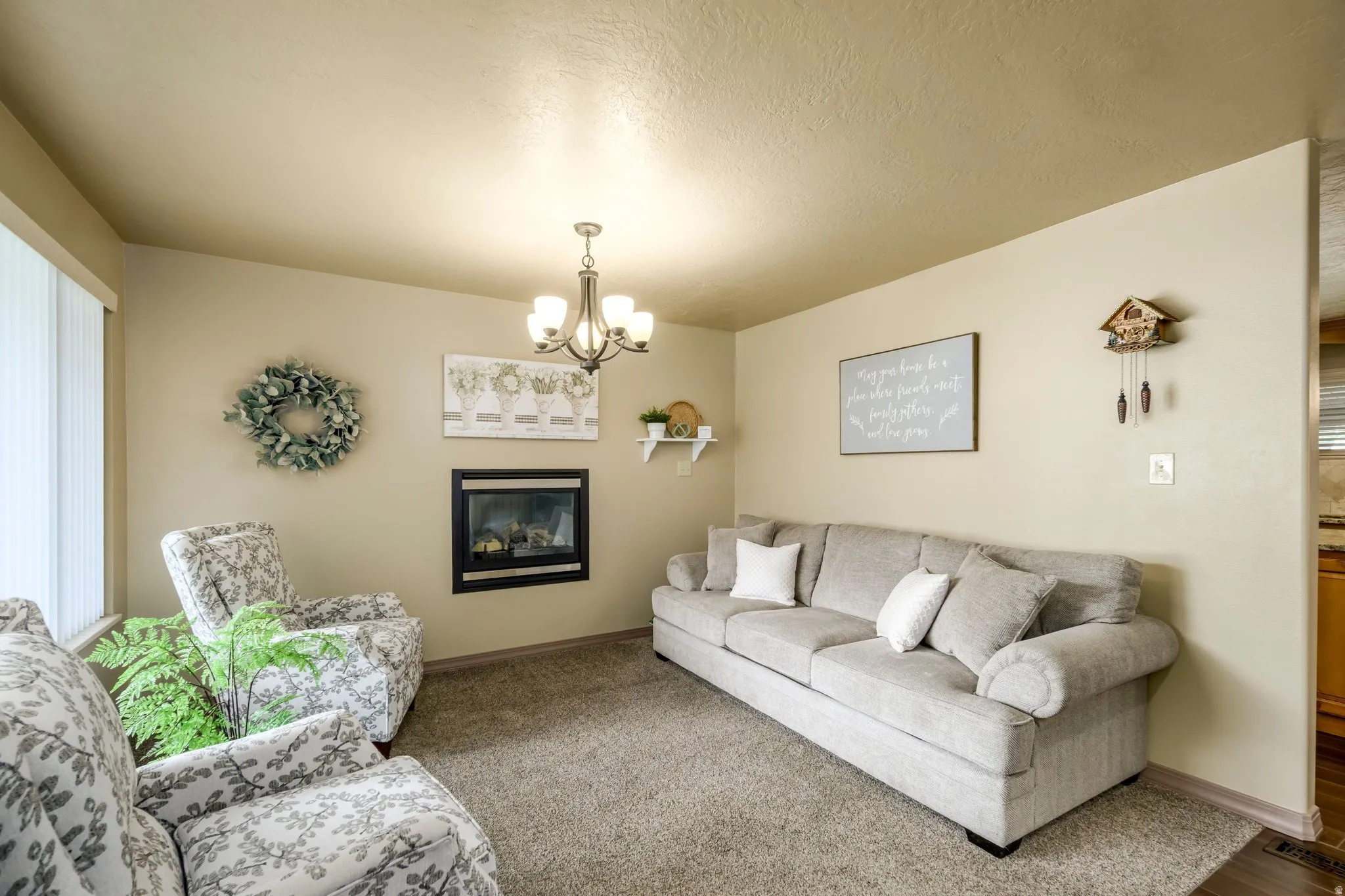 Living area featuring hanging lights, a textured ceiling, and a glass covered fireplace