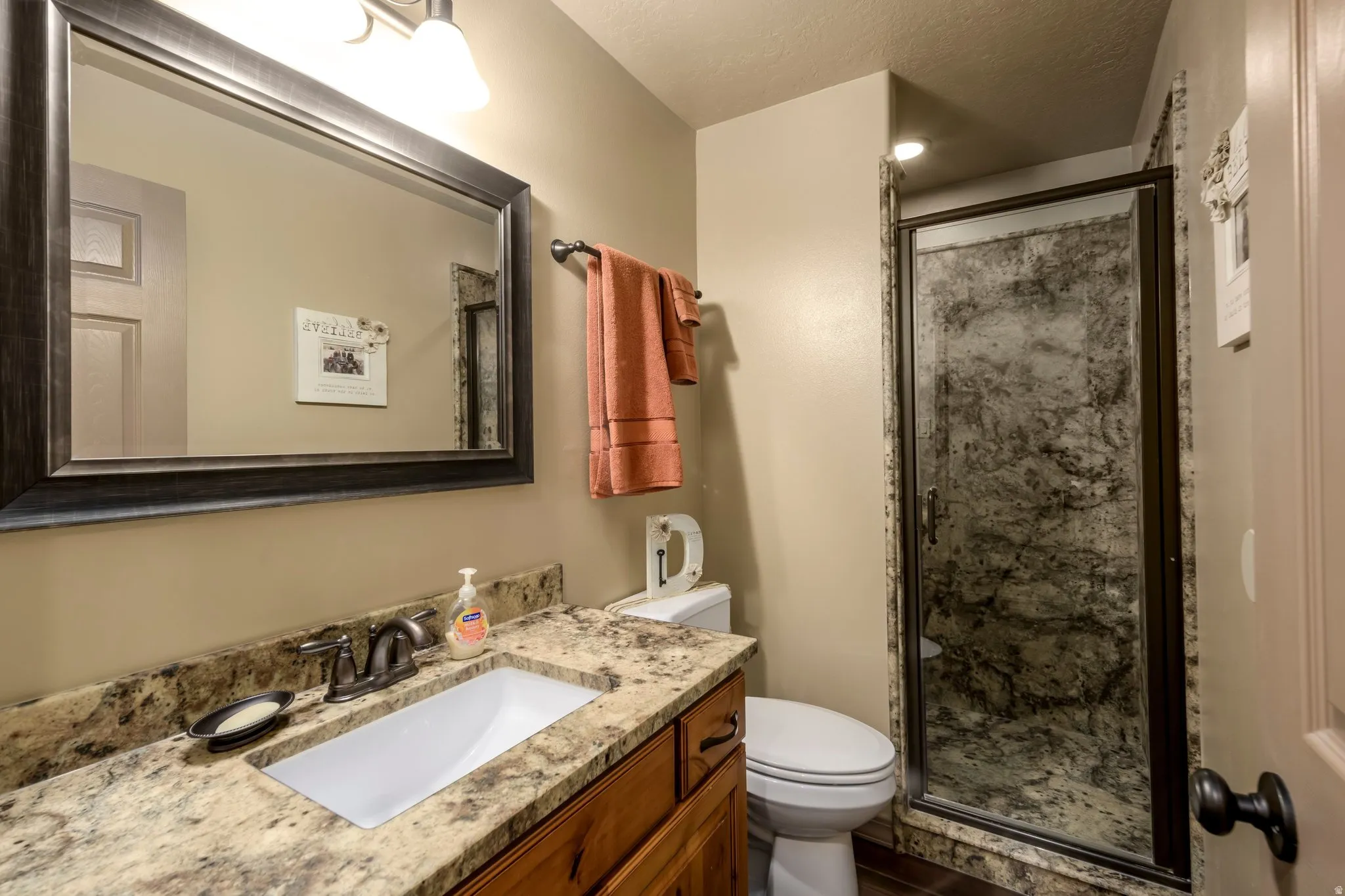 Full bathroom featuring vanity, a shower stall, and a textured ceiling