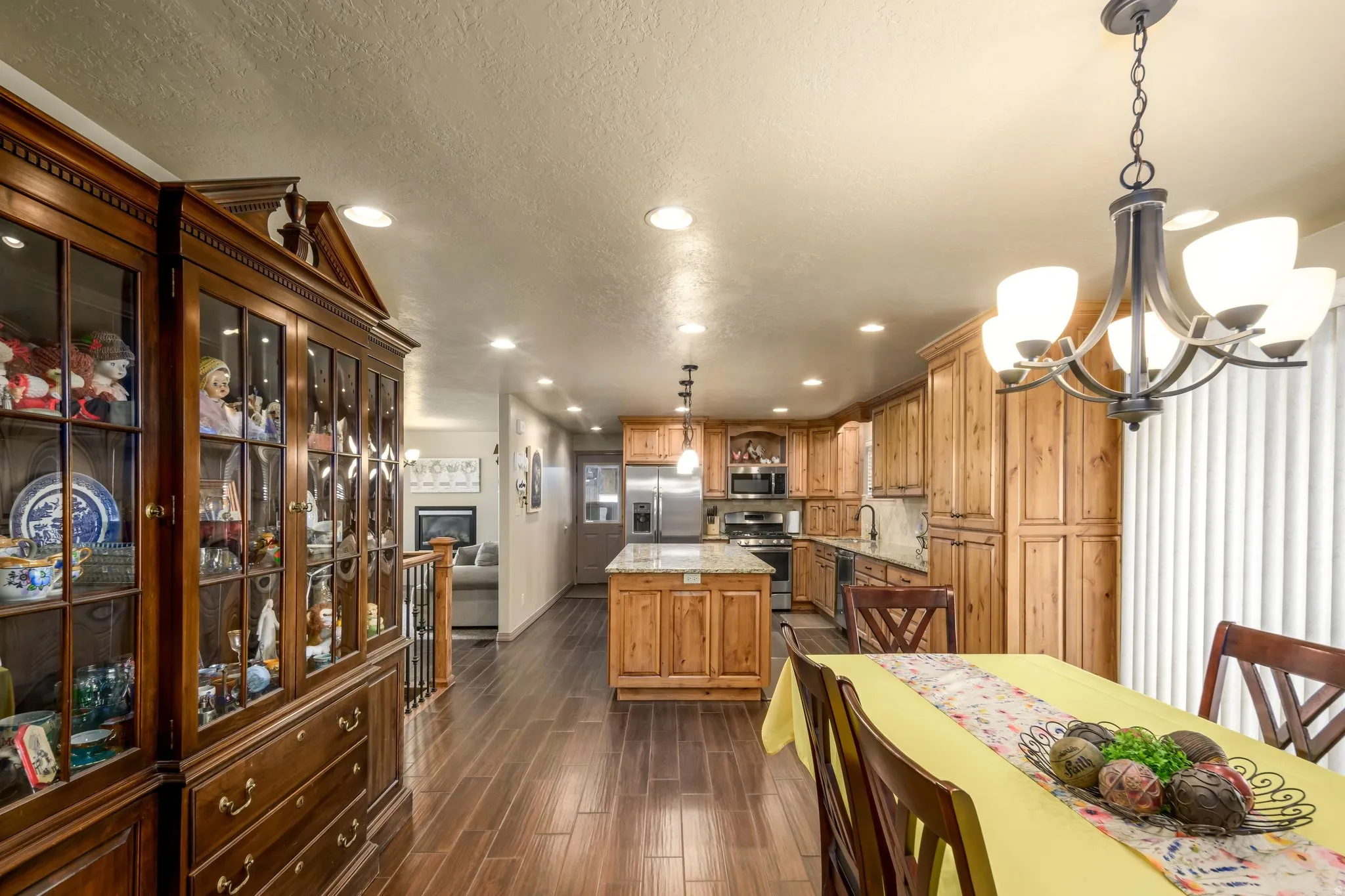 Kitchen featuring glass fronted cabinets, light stone counters, suspended lighting, wood tiled floors, and stainless steel appliances