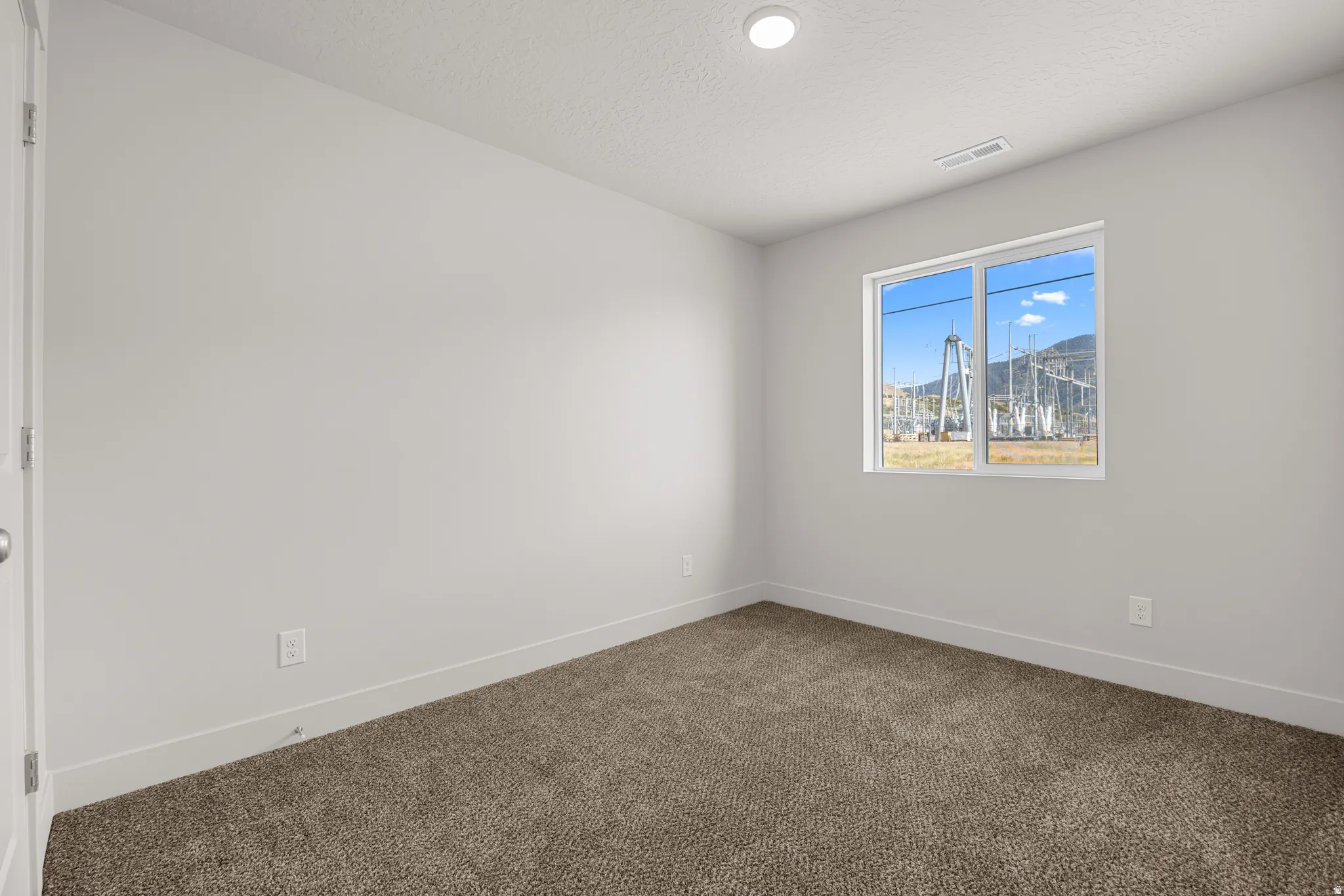 Unfurnished room with dark carpet and a textured ceiling