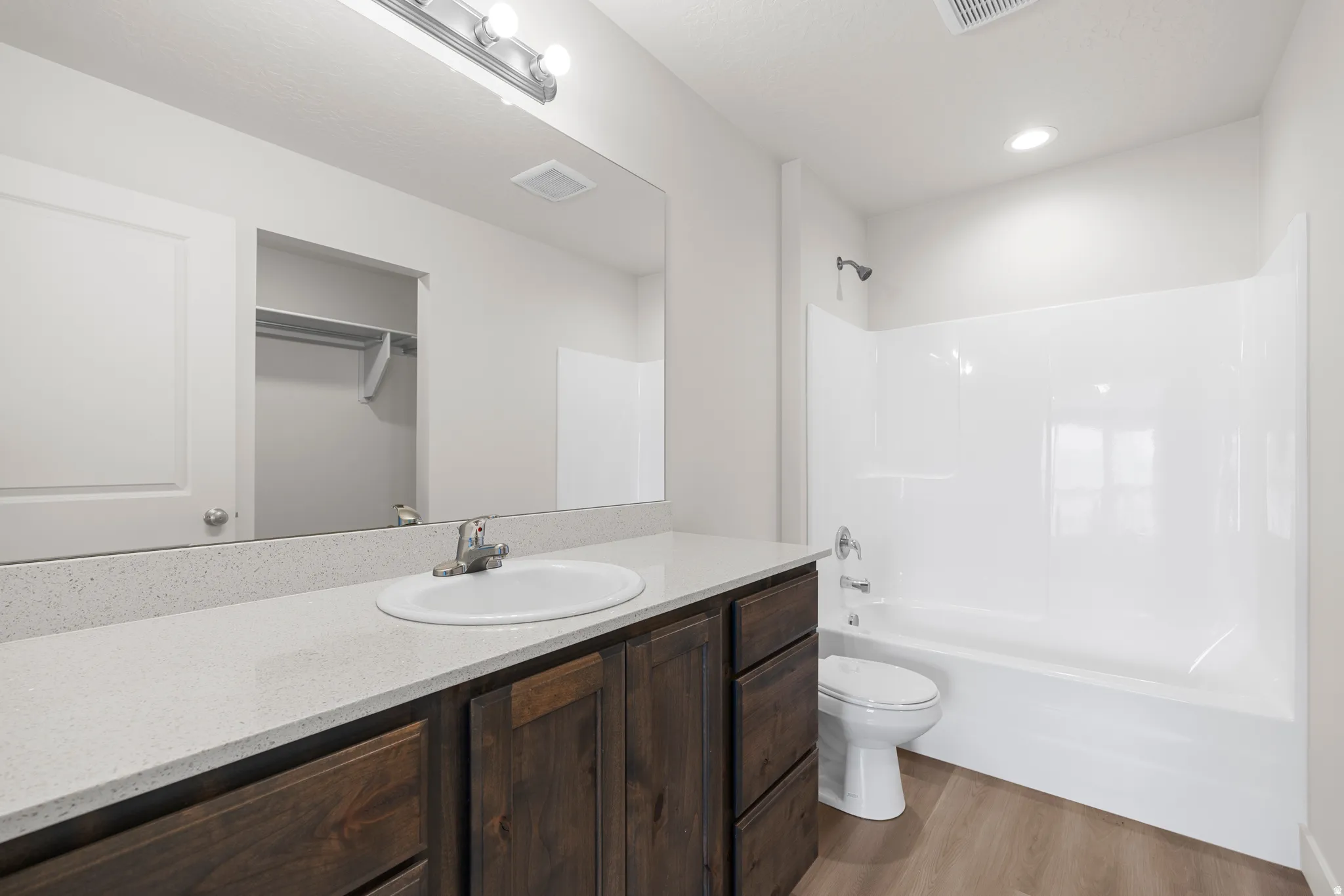 Bathroom with vanity, light wood-style floors, bathing tub / shower combination, and a spacious closet