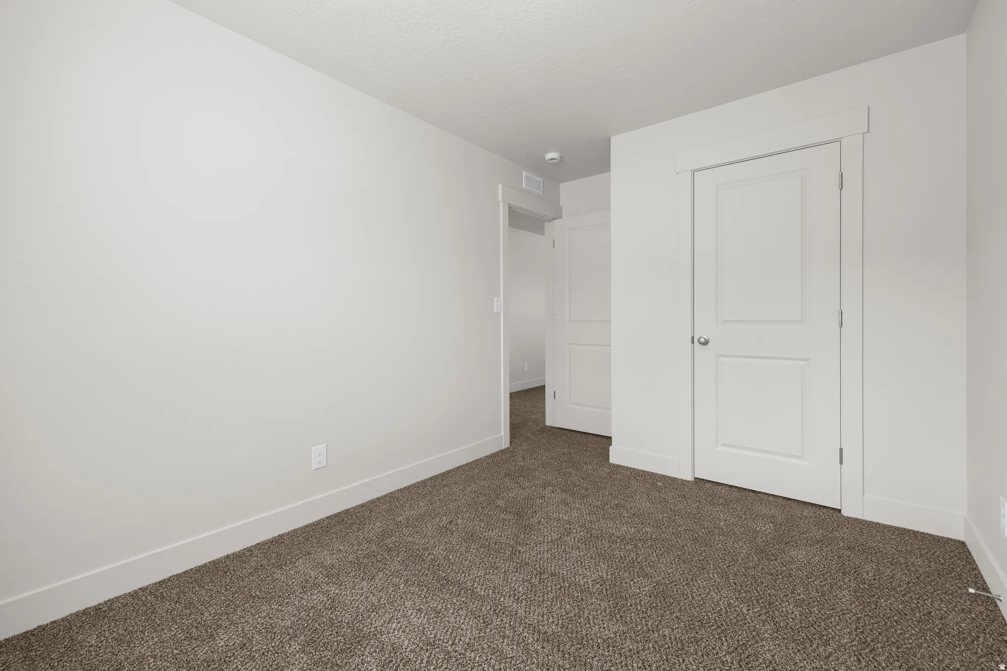 Unfurnished bedroom with dark colored carpet and a closet