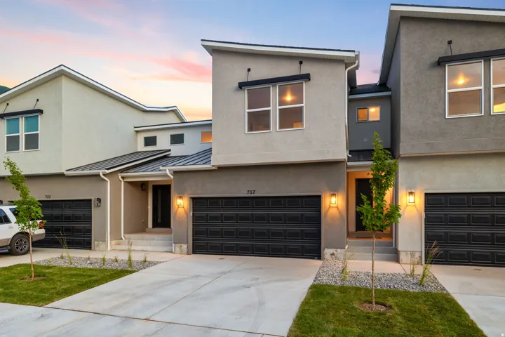 Contemporary home featuring a standing seam roof, driveway, a garage, and stucco siding