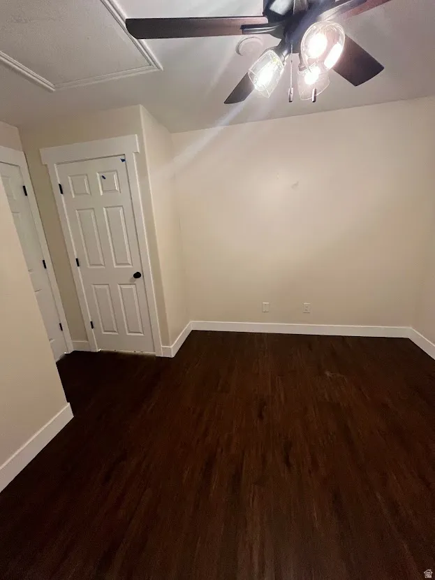 Empty room with dark wood-style floors and ceiling fan