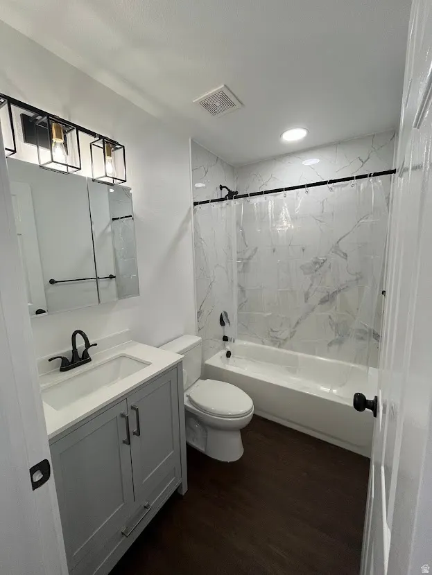 Hall bathroom featuring updated tub, oversized tile surround, plumbing fixtures, new cabinetry and lighting.