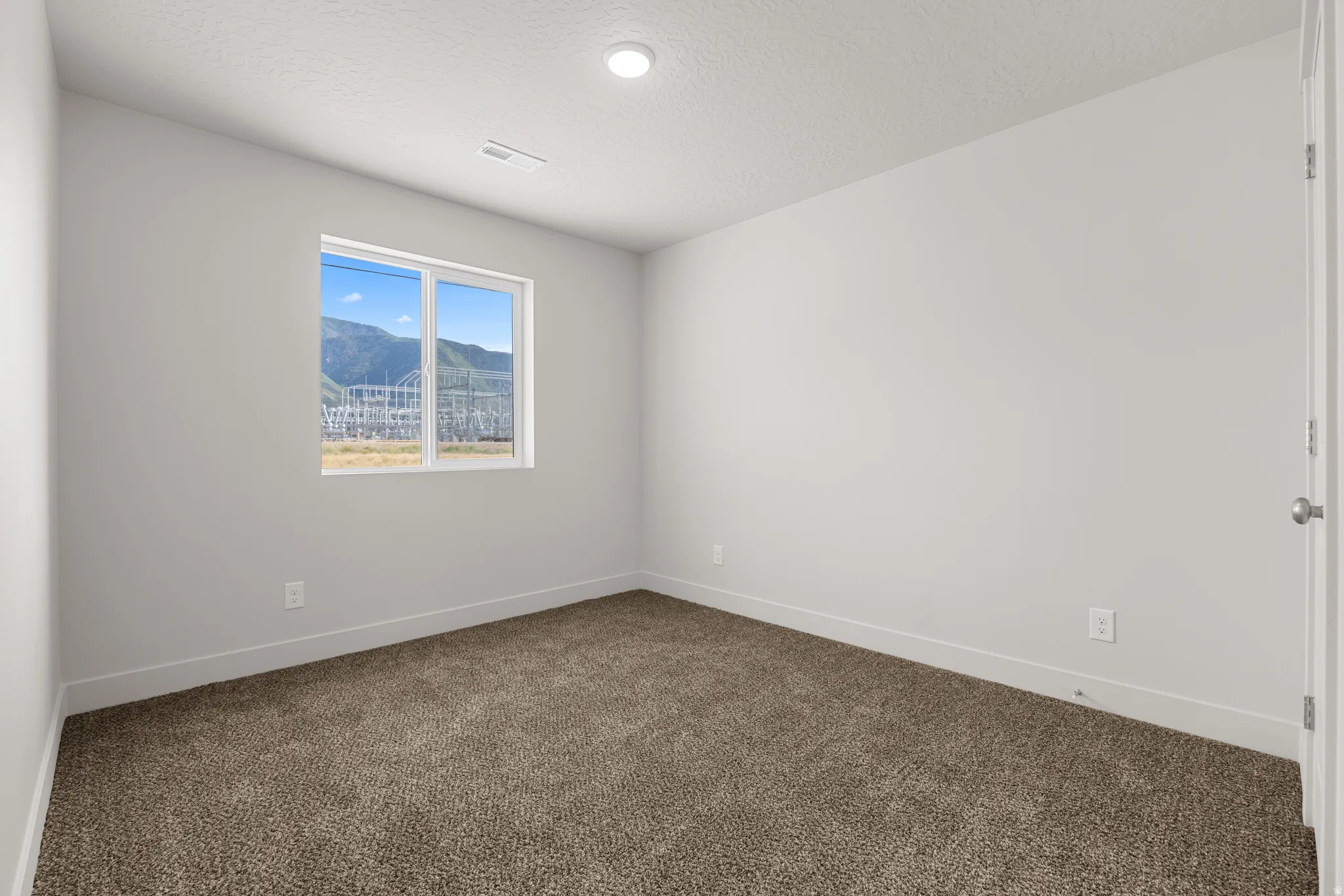 Spare room with a mountain view, dark carpet, and a textured ceiling