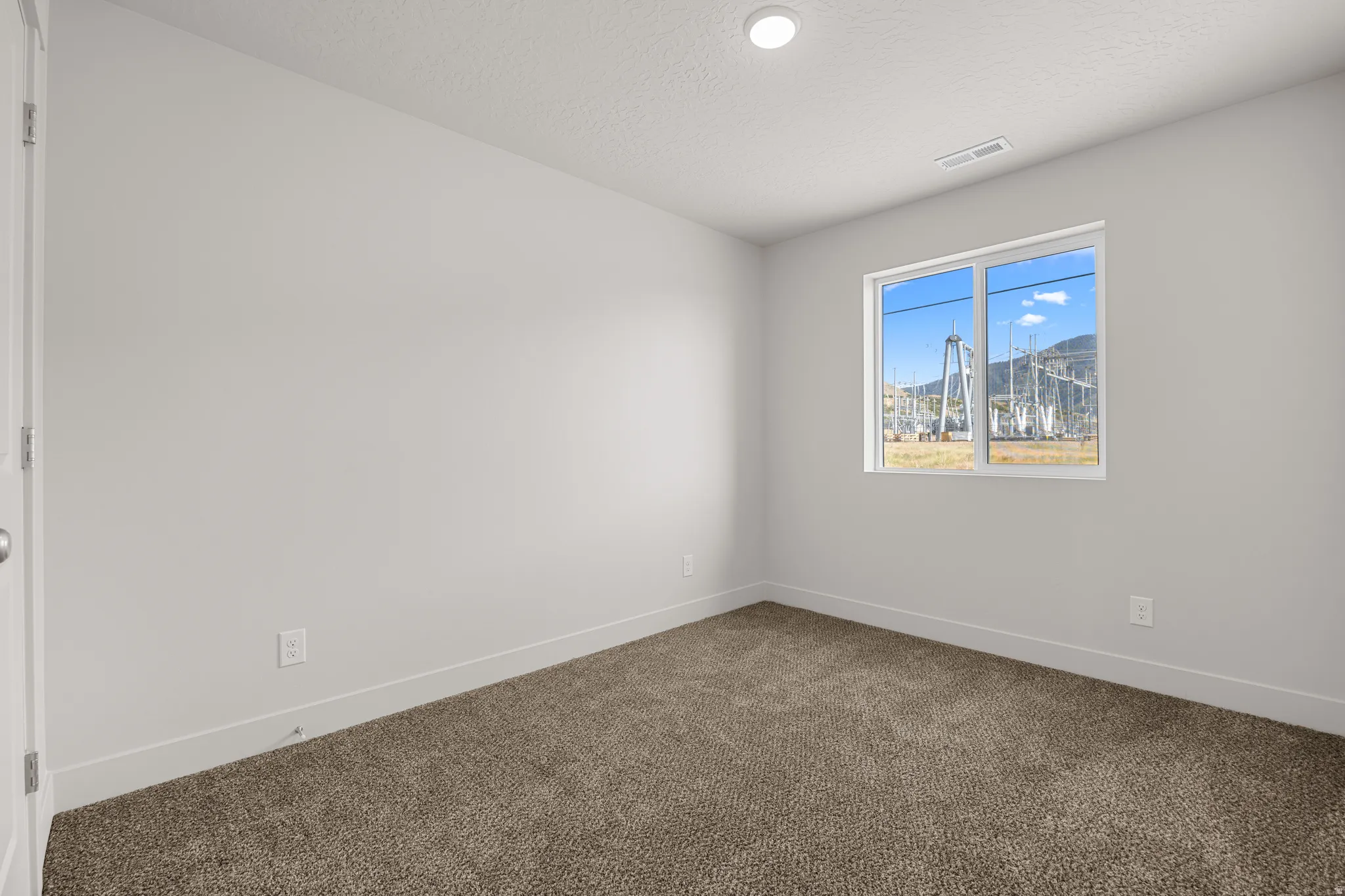 Empty room with dark carpet and a textured ceiling