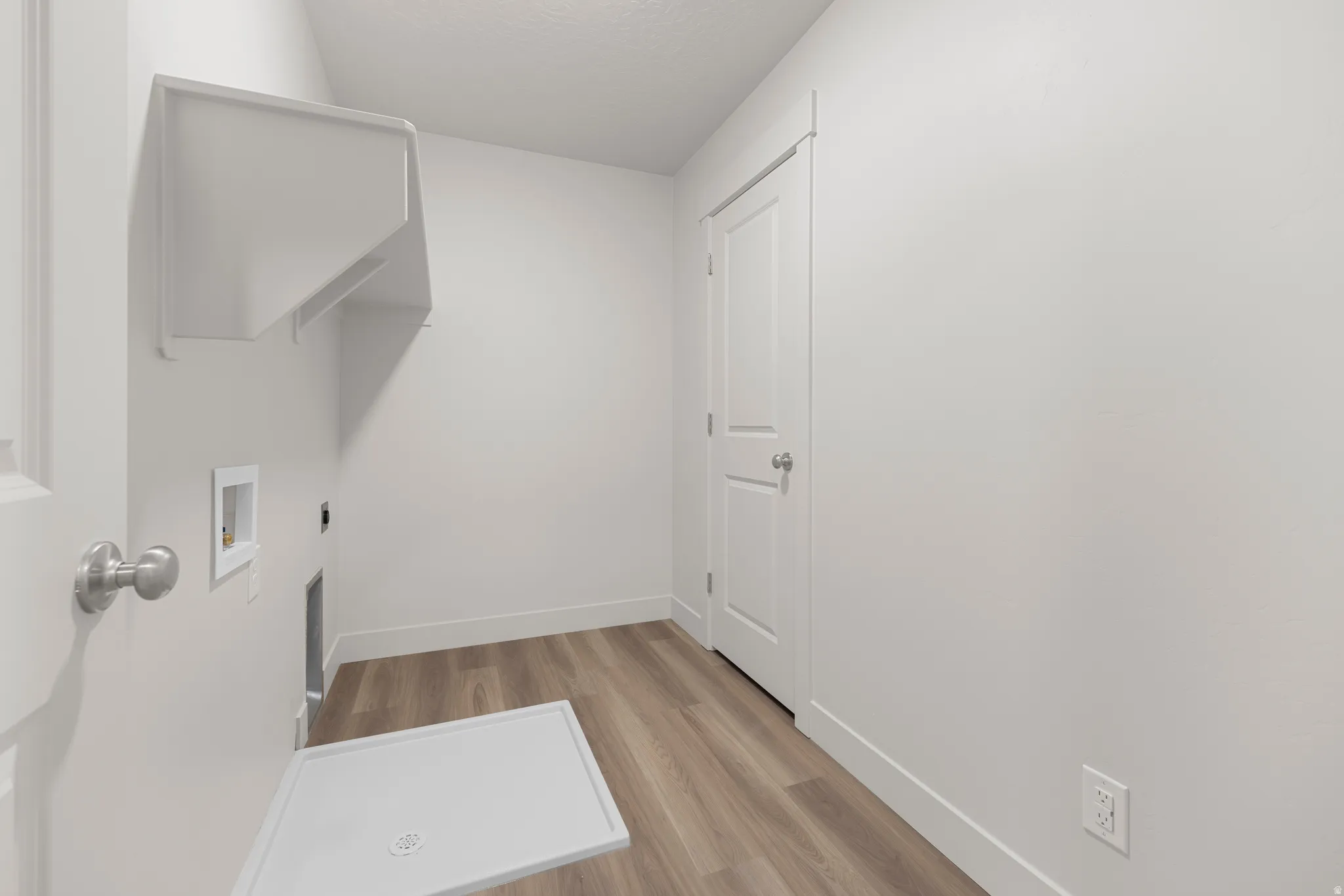 Laundry room featuring light wood-style floors, hookup for a washing machine, hookup for an electric dryer, and a textured ceiling