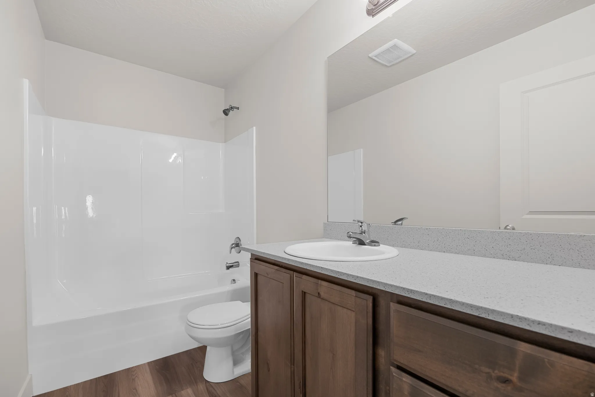 Full bath featuring vanity, dark wood-type flooring, shower / tub combination, and a textured ceiling