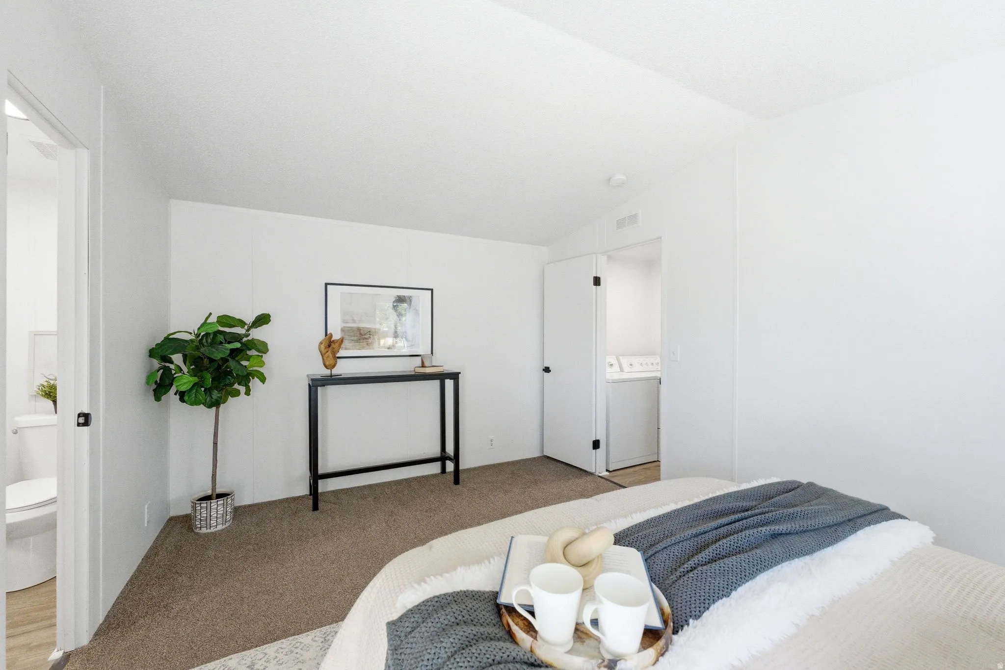 Bedroom featuring vaulted ceiling, light carpet, washer / clothes dryer, and connected bathroom