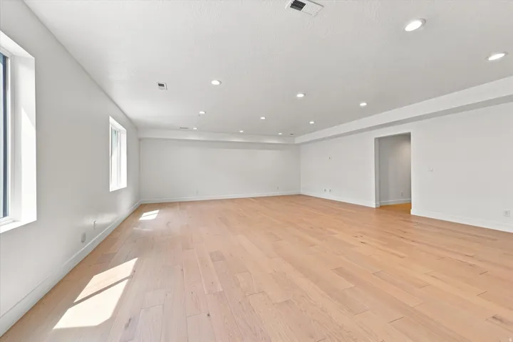 Spacious room featuring wood-finish flooring, recessed lighting, and multiple windows