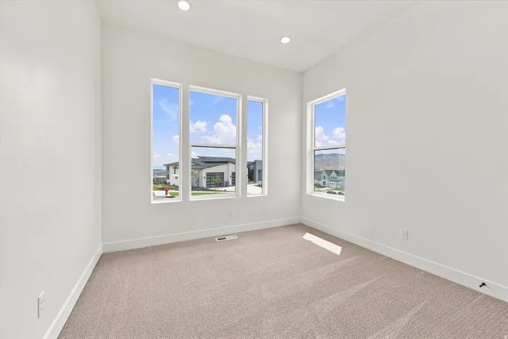 Recessed lighting, light-toned walls, and neutral carpet flooring