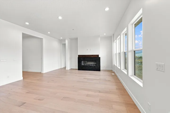 Recessed lighting, wood-finish flooring, a modern black fireplace surround, a dark wood mantel, and multiple windows