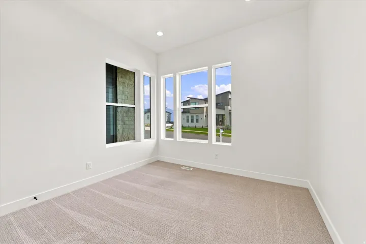 Recessed ceiling lighting, multiple large windows, neutral-toned carpeting, and crisp white walls