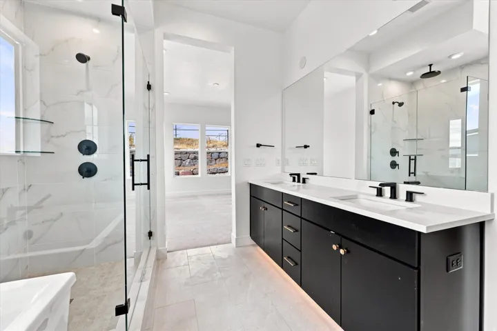 Sleek bathroom featuring a spacious glass-enclosed shower, dual vanity with undermount sinks, and contemporary matte black fixtures