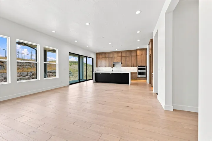 Spacious open-concept interior featuring light wood-finish flooring, recessed lighting, and large windows