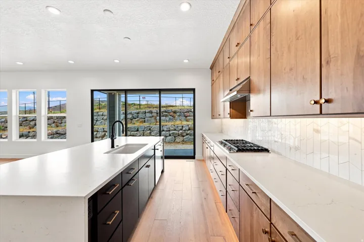 Sleek kitchen with a large central island, white countertops, and wood-finish cabinetry