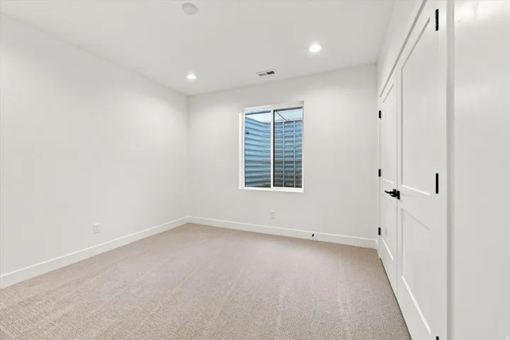 Recessed lighting, light-colored carpeting, white walls, white doors, and black door hardware