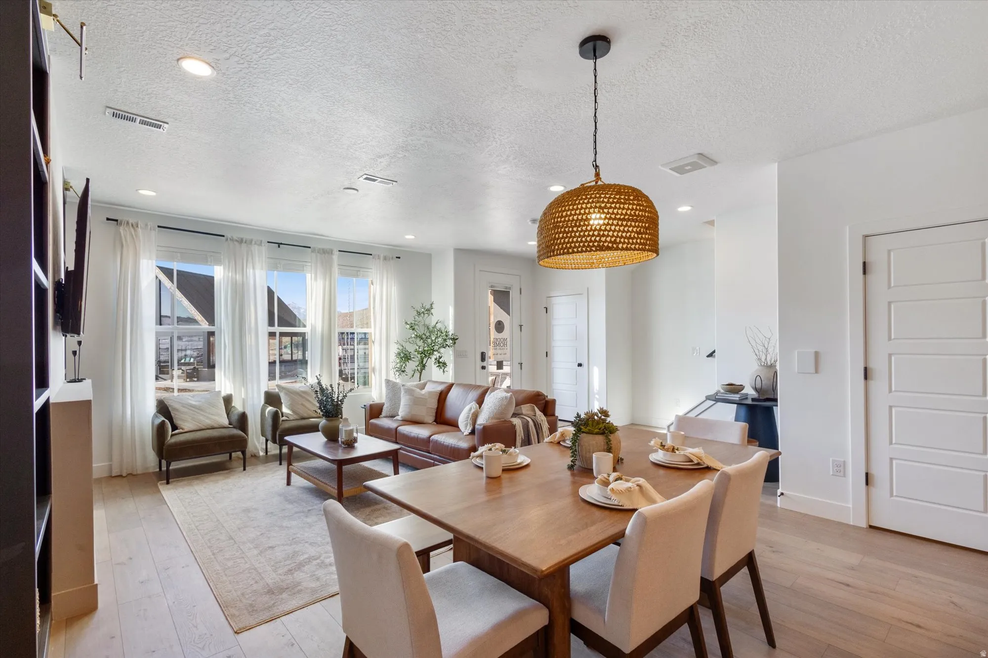 Dining room with light wood-style flooring, a textured ceiling, and recessed lighting