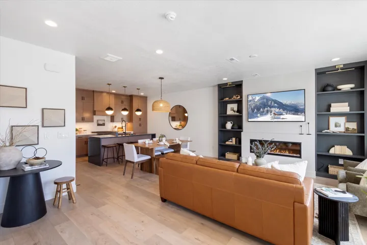 Living room featuring light wood-style flooring, built in shelves, a glass covered fireplace, and recessed lighting