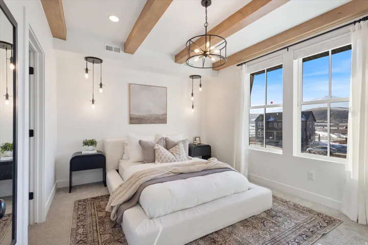 Bedroom with carpet floors, beam ceiling, and suspended lighting