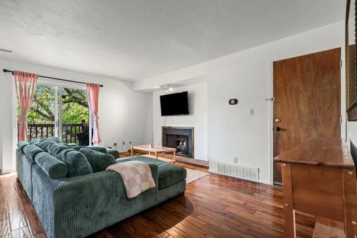 Living area featuring a brick fireplace, hardwood floors, and a textured ceiling