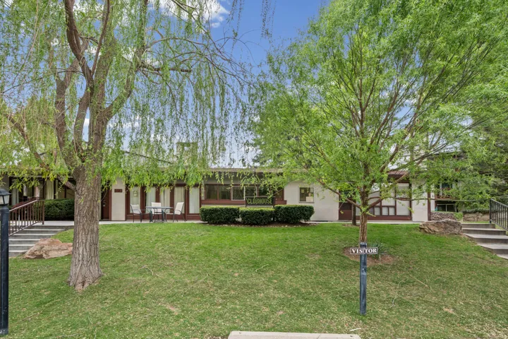 View of front of Clubhouse featuring stucco siding, a front lawn, and a patio area