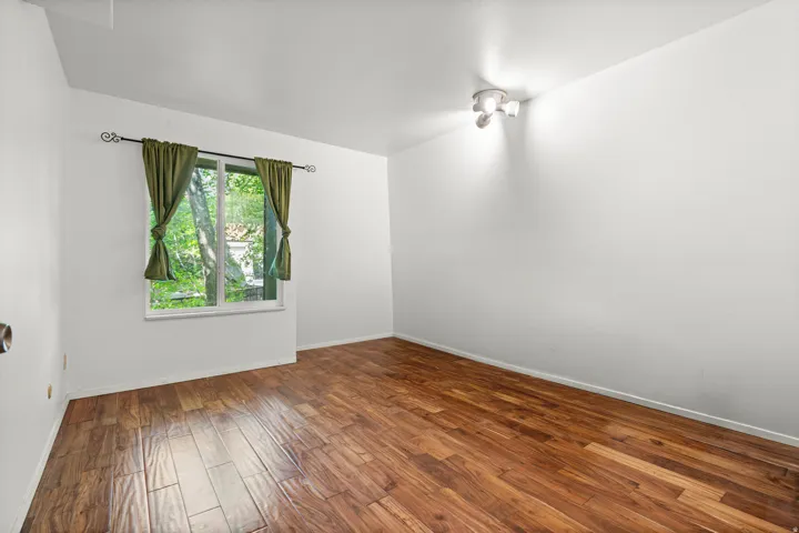 Unfurnished room with dark hardwood floors and baseboards