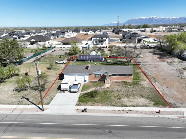 Aerial perspective of suburban area with property parcel outlined and a mountain backdrop