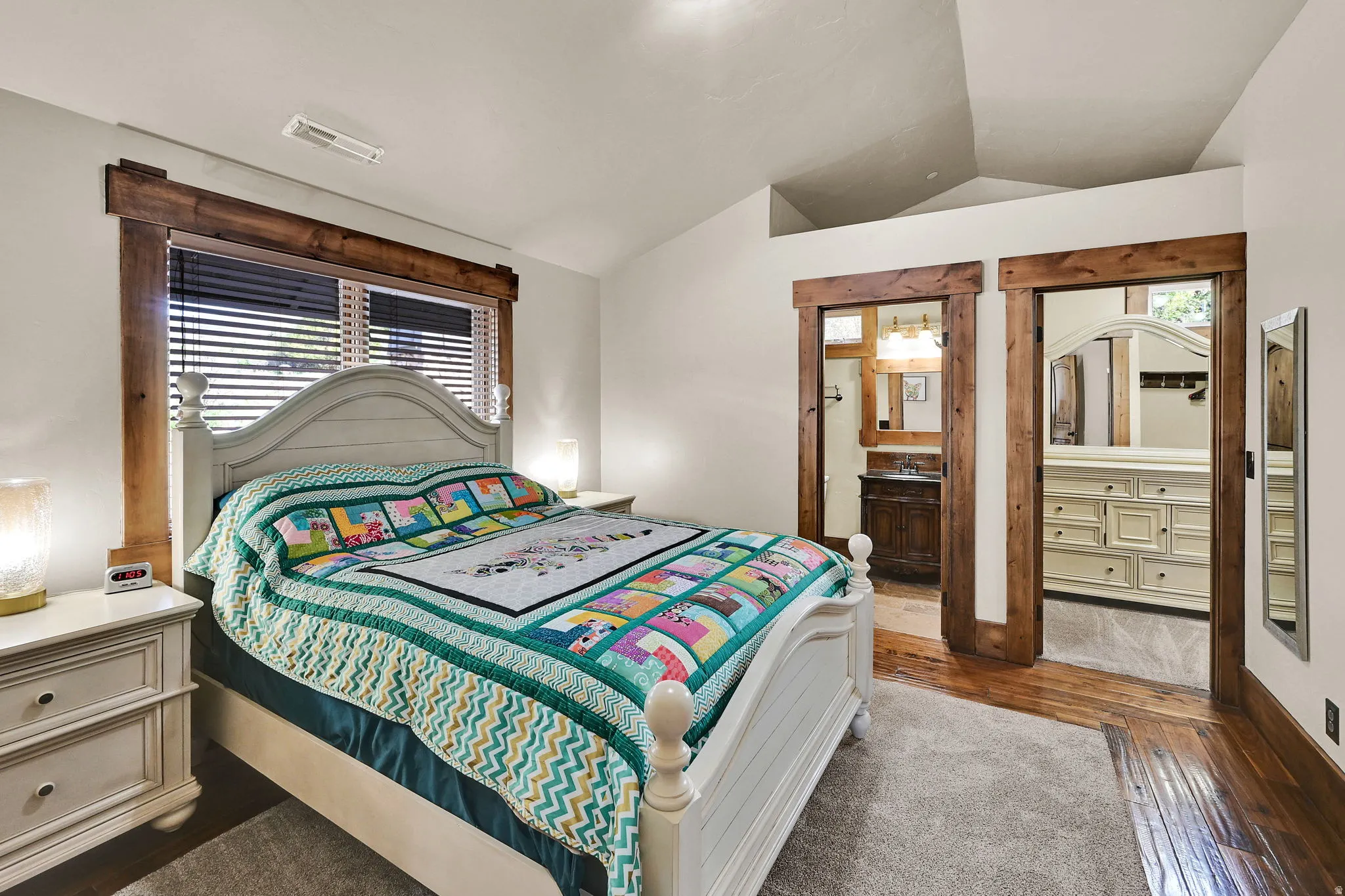 Bedroom featuring lofted ceiling, dark wood finished floors, and ensuite bath