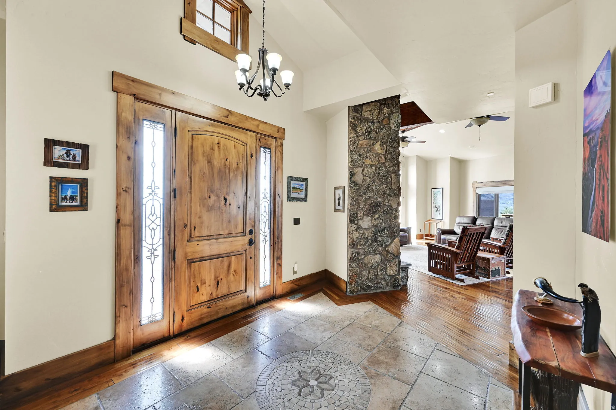 Foyer with stone tile floors, a ceiling fan, a high ceiling, and a chandelier