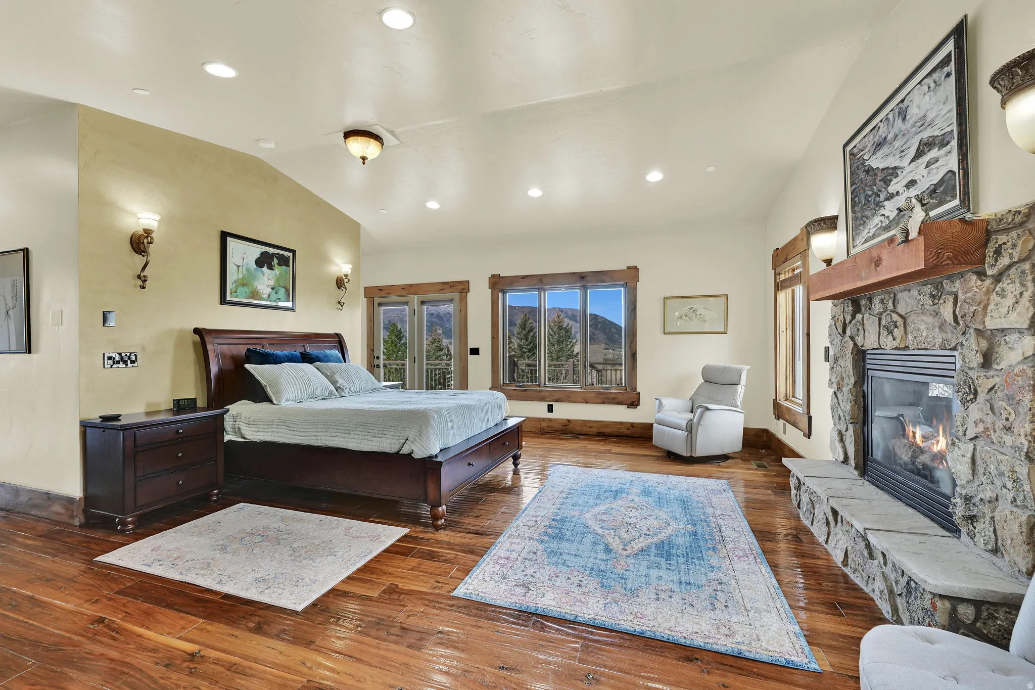 Bedroom featuring lofted ceiling, access to outside, a fireplace, wood-type flooring, and recessed lighting