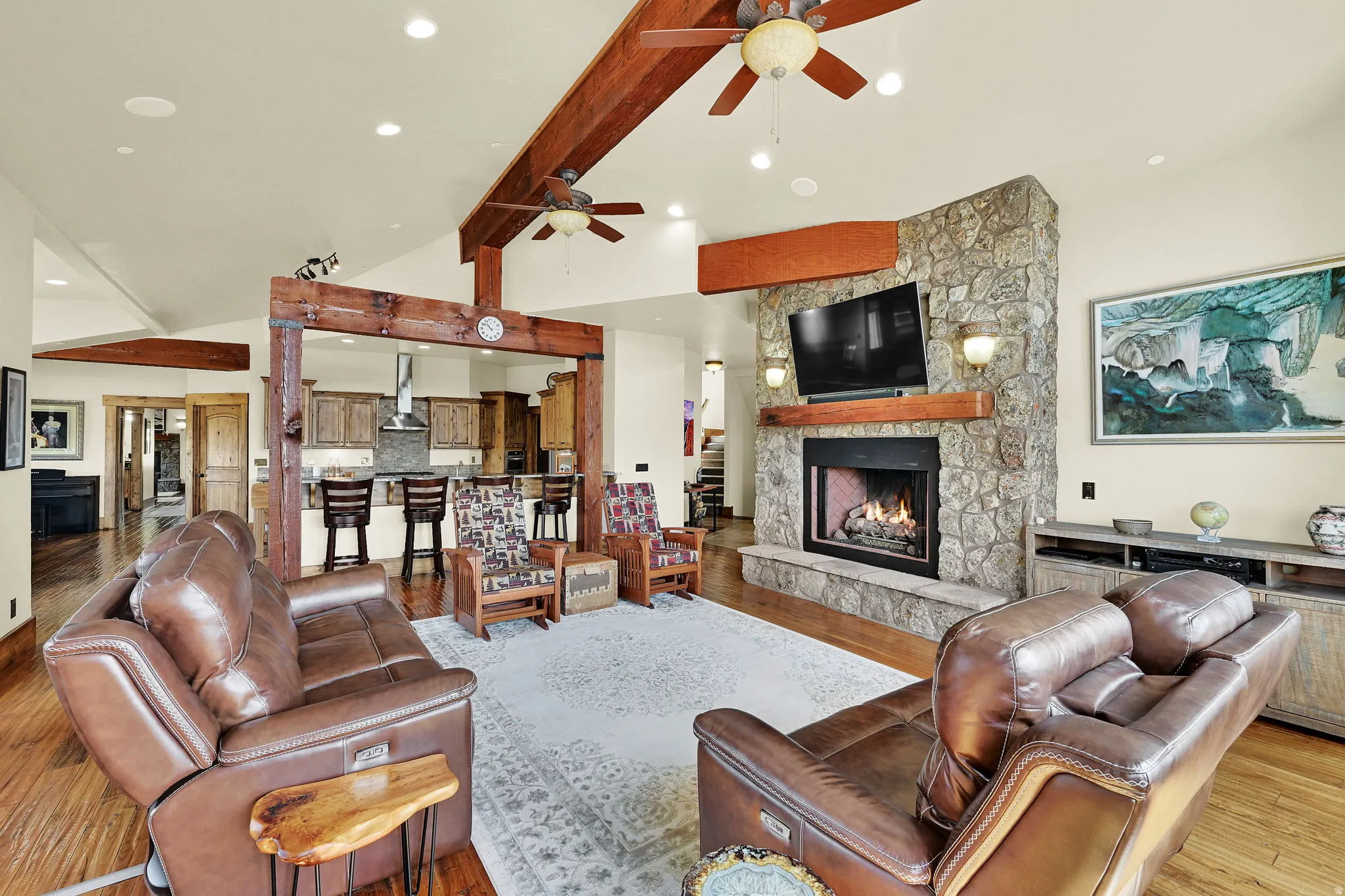 Living room with a stone fireplace, ceiling fan, recessed lighting, light wood-style floors, and vaulted ceiling