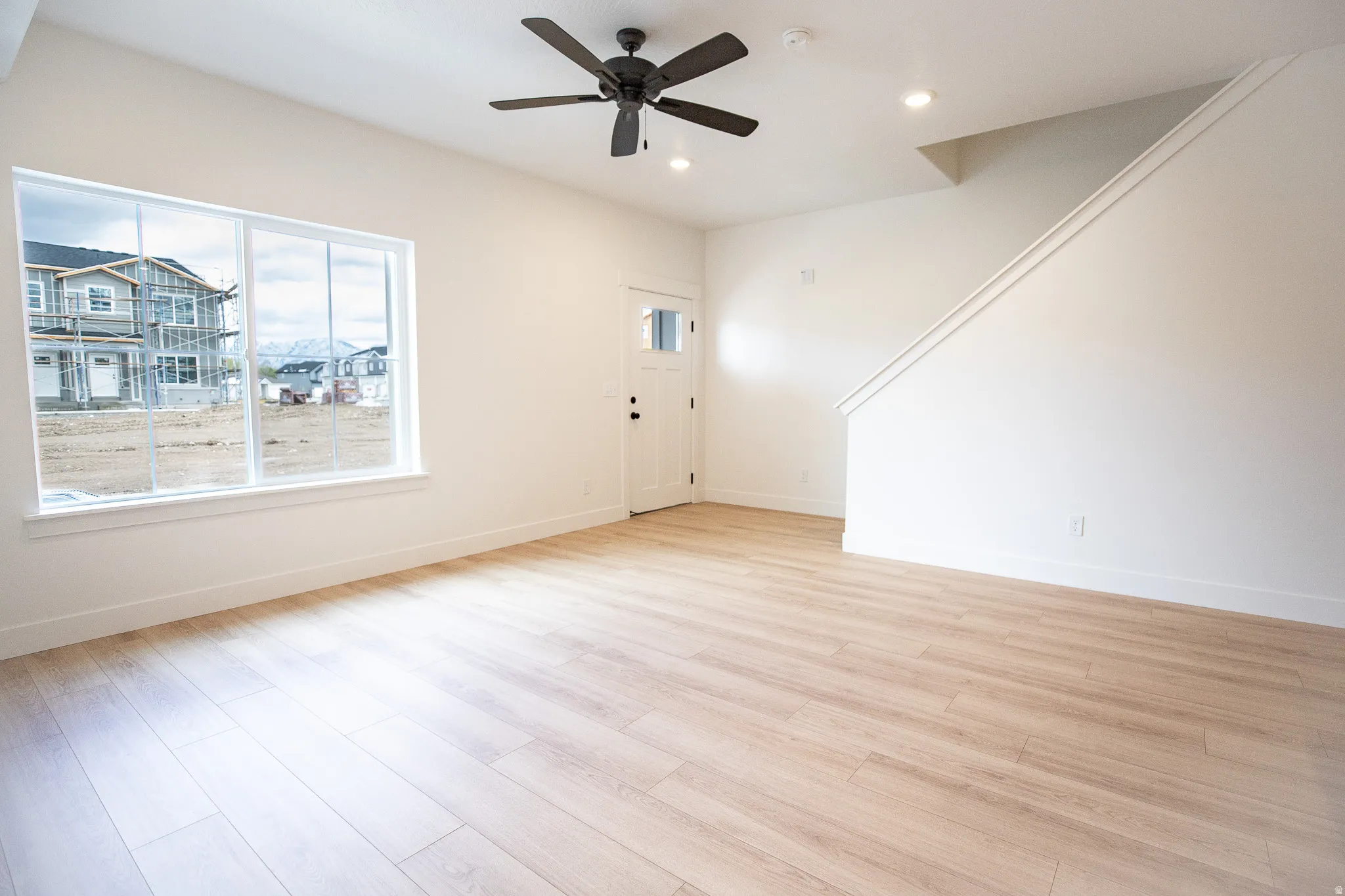 Family room with large front window, a ceiling fan, recessed lighting, and wood laminate flooring throughout