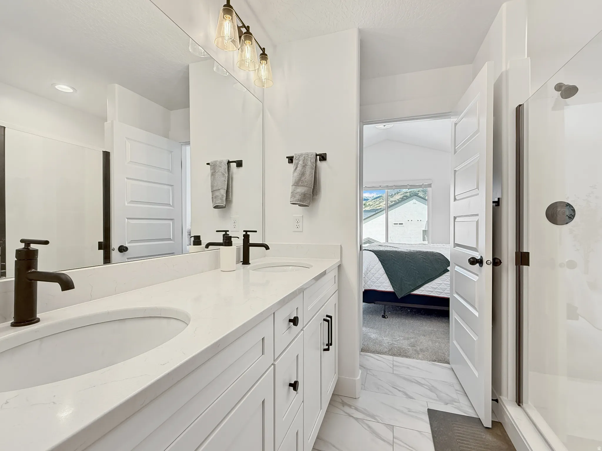 Full bath with a shower stall, ensuite bathroom, double vanity, and light marble finish flooring