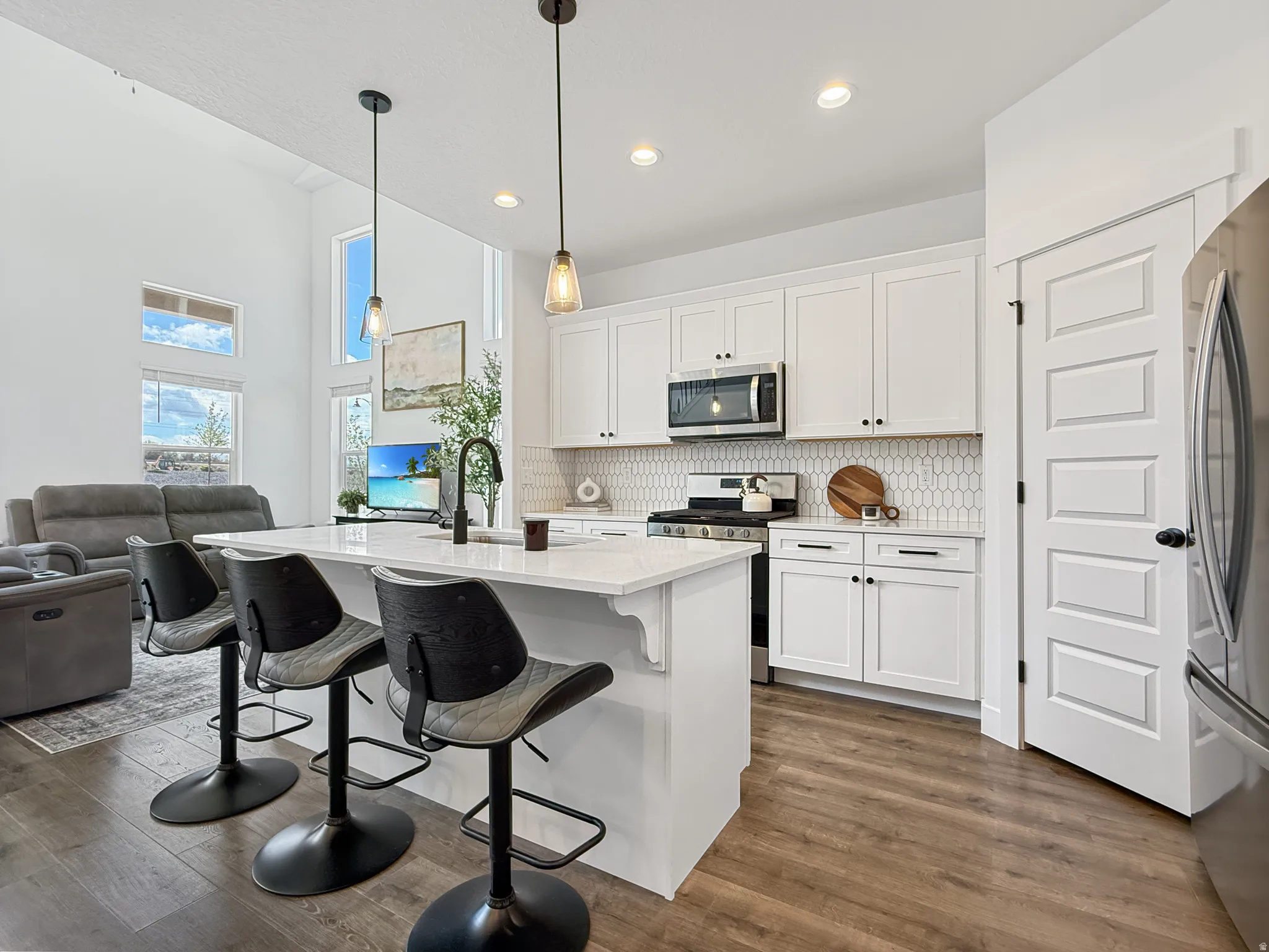 Kitchen featuring a breakfast bar, open floor plan, white cabinets, stainless steel appliances, and dark wood-style floors